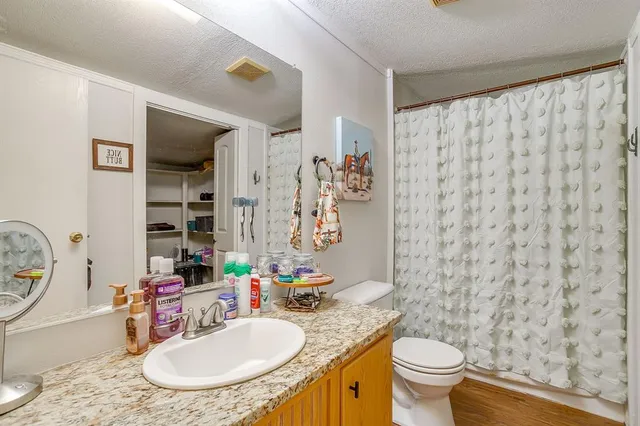 a bathroom with a granite countertop sink mirror vanity and toilet