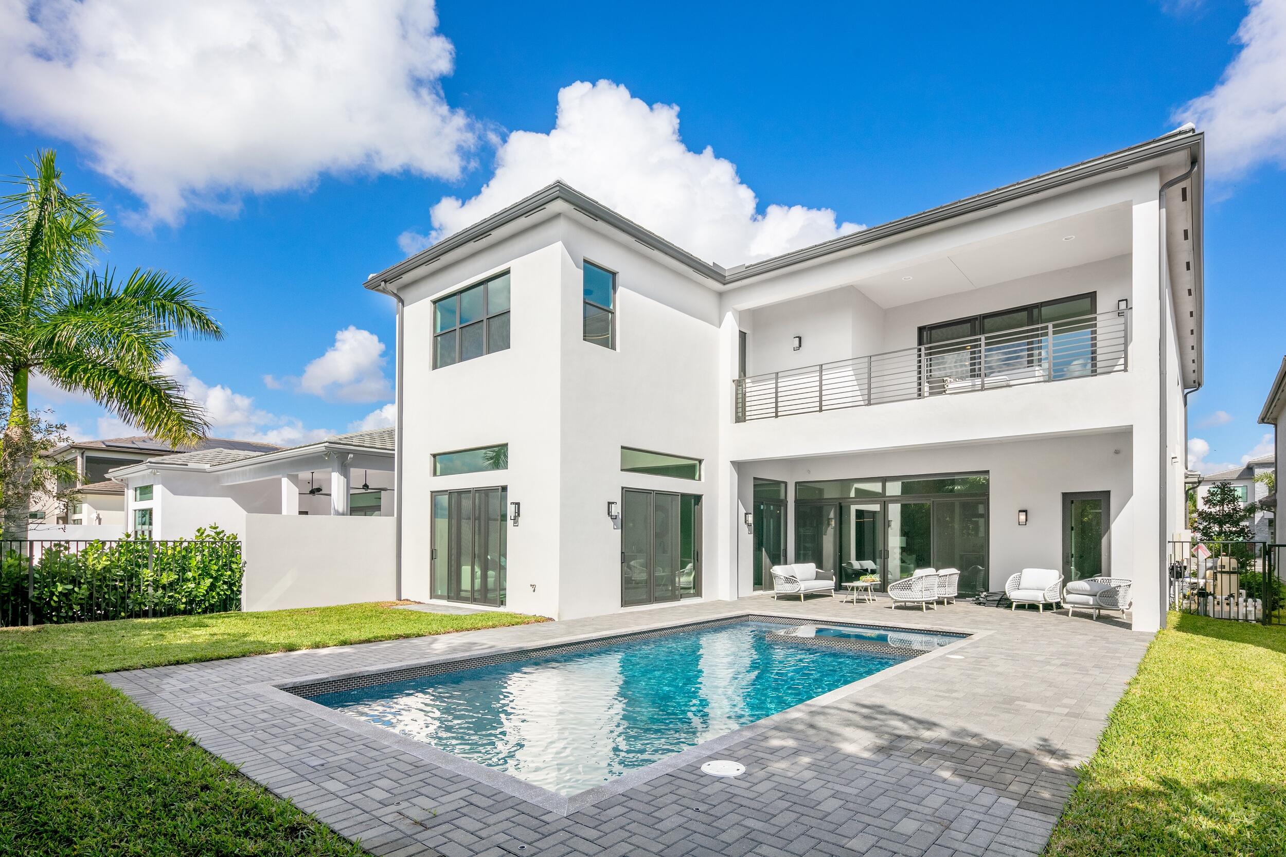 9132 Benedetta Place Boca Raton, FL 33496 - Photo 23 of 50 a view of a white house with a swimming pool and a lawn chairs next to a yard