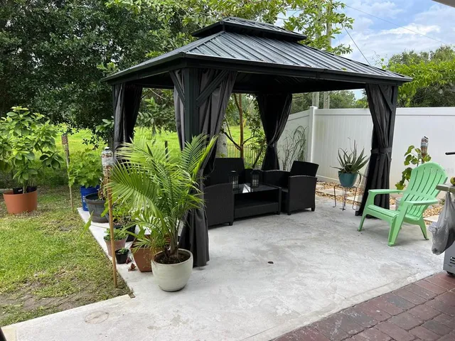 a backyard of a house with table and chairs potted plants
