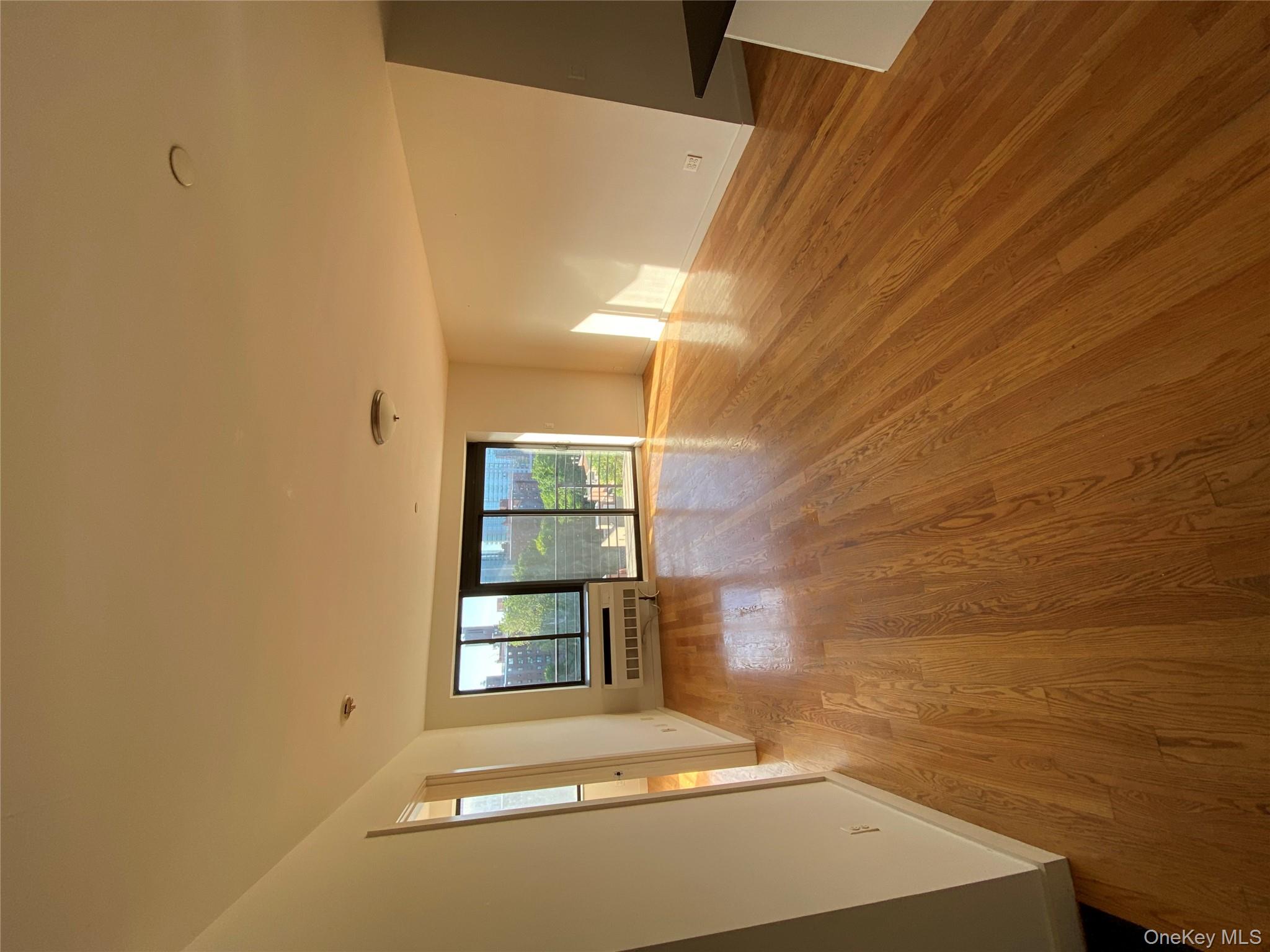 132-35 41st Road, Unit 10D Queens, NY 11355 - Photo 4 of 18 a view of empty room with wooden floor and fan