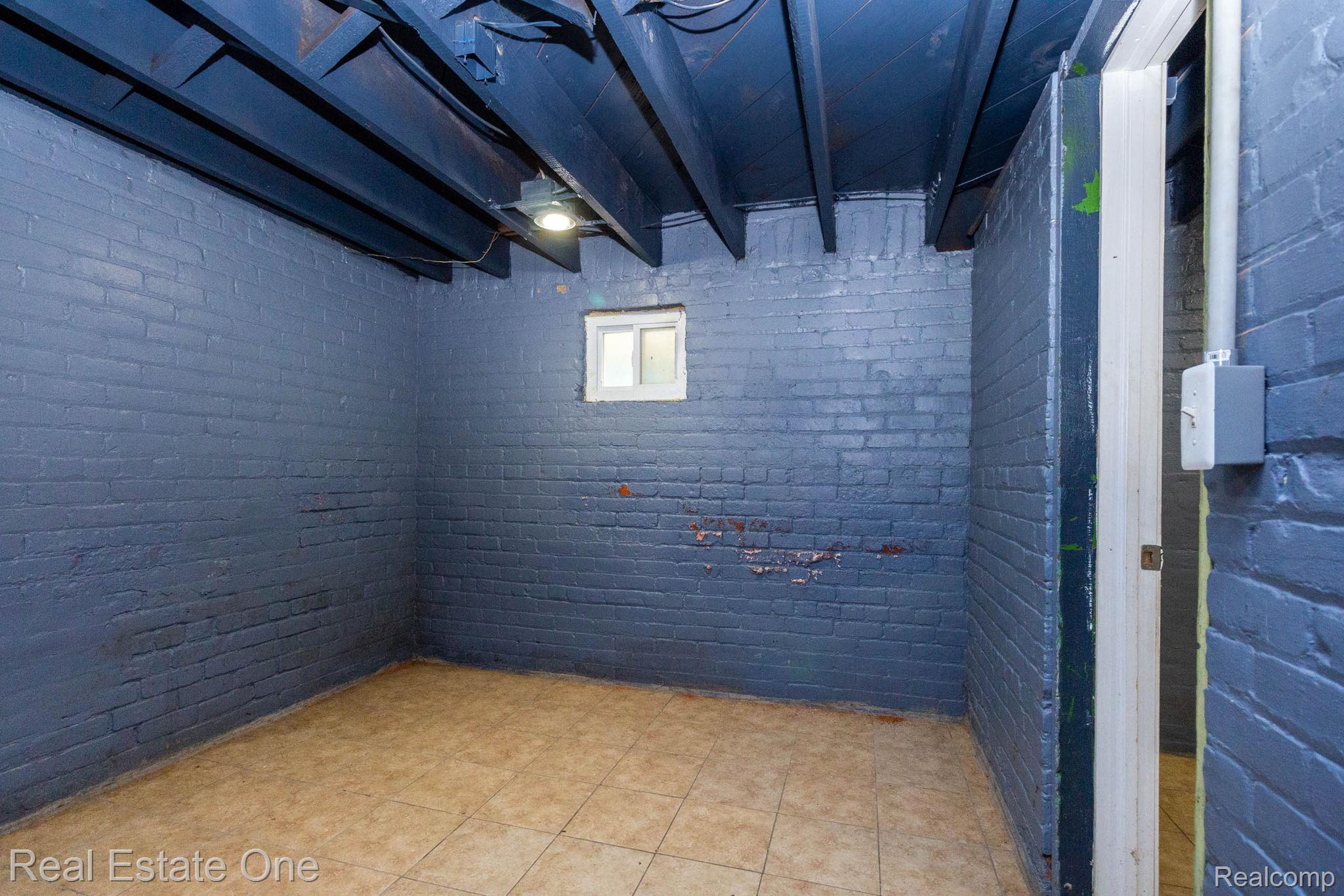 5485 Springwells Street Detroit, MI 48210 - Photo 40 of 47 Painted brick walls with tiled flooring, exposed ceiling joists, and a small window