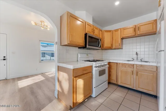a kitchen with stainless steel appliances granite countertop white cabinets a sink a stove a microwave and island