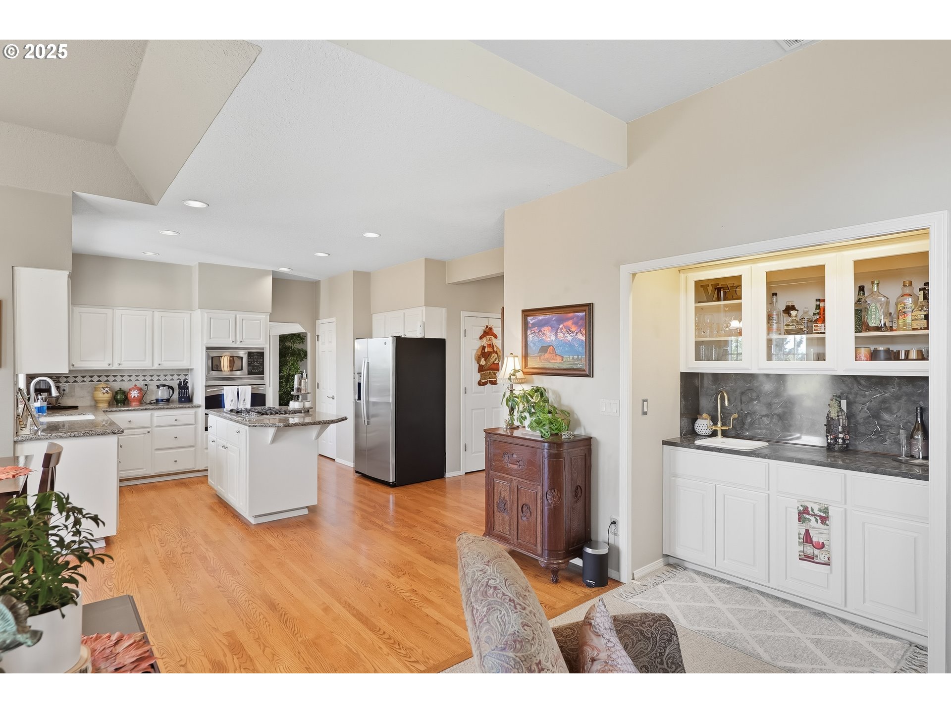 14362 Southwest 134th Drive Portland, OR 97224 - Photo 12 of 36 a kitchen with stainless steel appliances kitchen island granite countertop a refrigerator a stove a sink a dining table and chairs with wooden floor