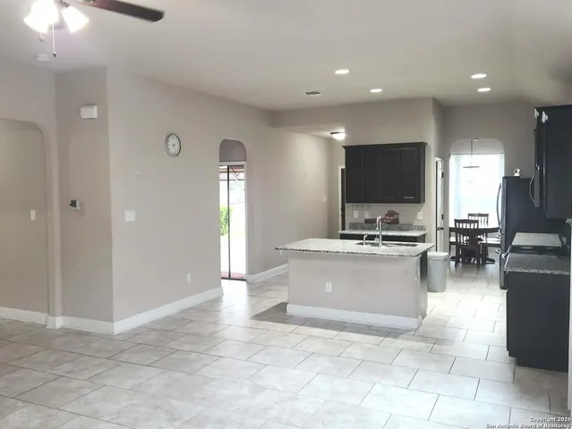 a view of living room with stainless steel appliances granite countertop couches a fireplace and a flat screen tv