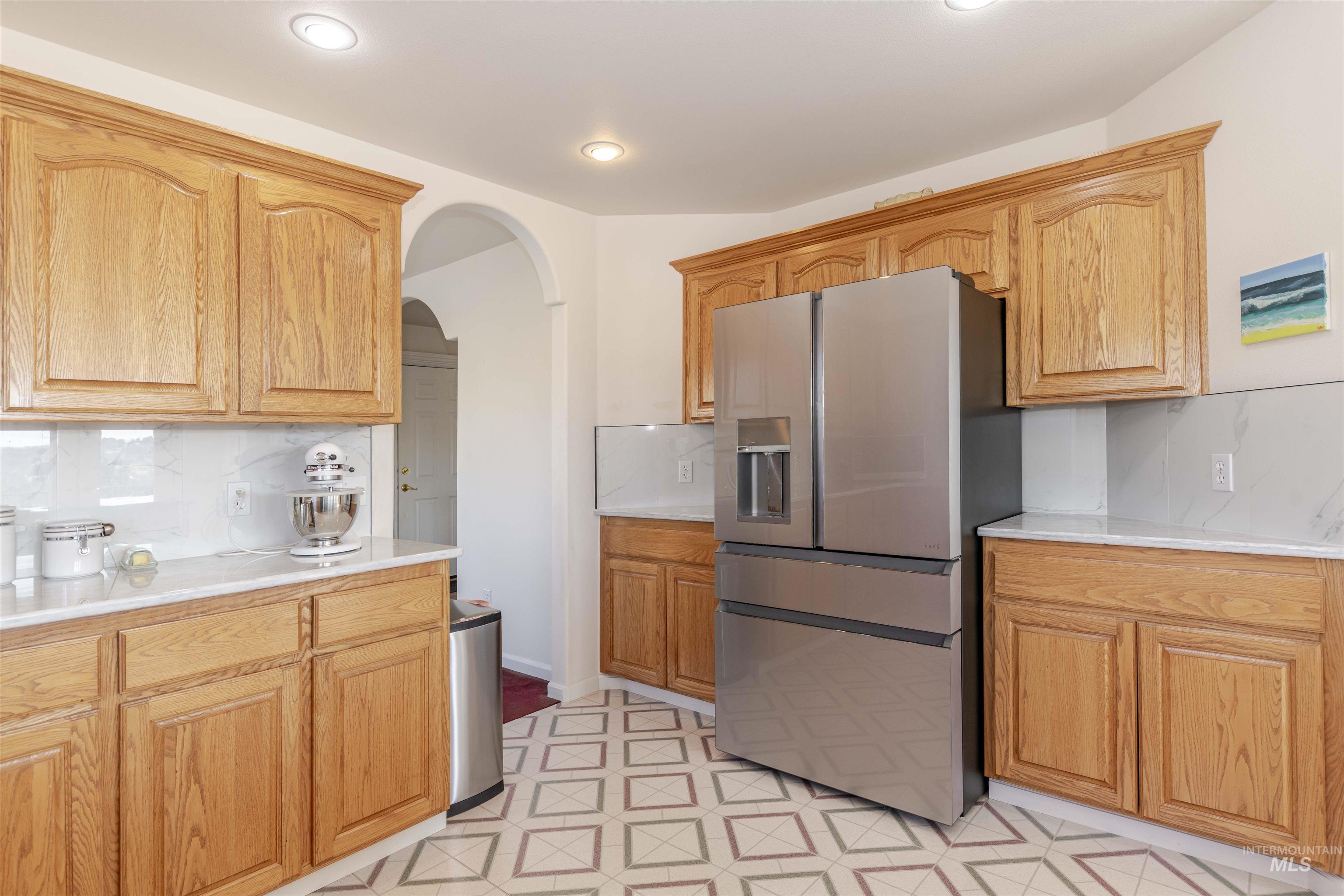 331 Reservoir Drive Lewiston, ID 83501 - Photo 8 of 42 Kitchen with stainless steel fridge with ice dispenser, decorative backsplash, arched walkways, and light flooring