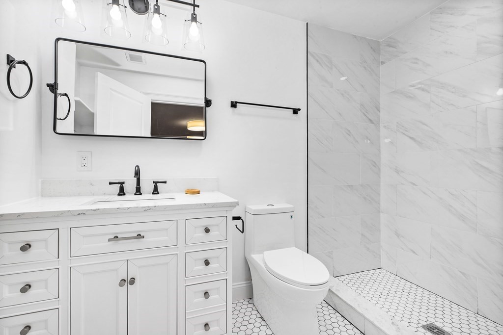 216 Grove Street Randolph, MA 02368 - Photo 20 of 34 a bathroom with a granite countertop sink a toilet and a mirror