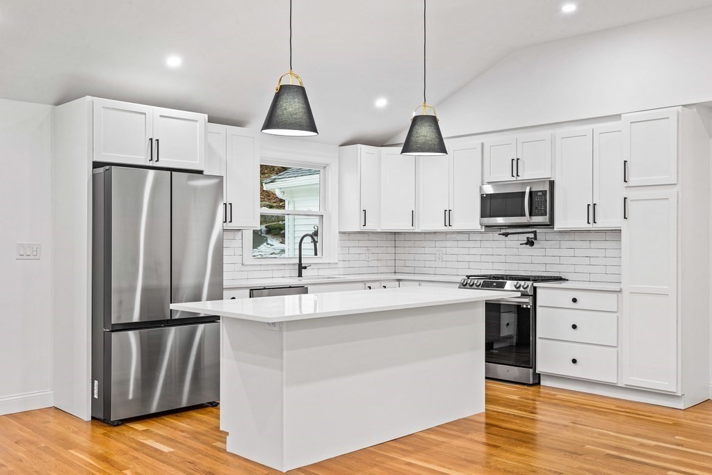 216 Grove Street Randolph, MA 02368 - Photo 7 of 34 a kitchen with kitchen island a sink stainless steel appliances and cabinets