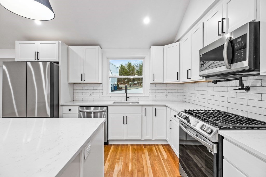 216 Grove Street Randolph, MA 02368 - Photo 8 of 34 a kitchen with stainless steel appliances a stove microwave and sink