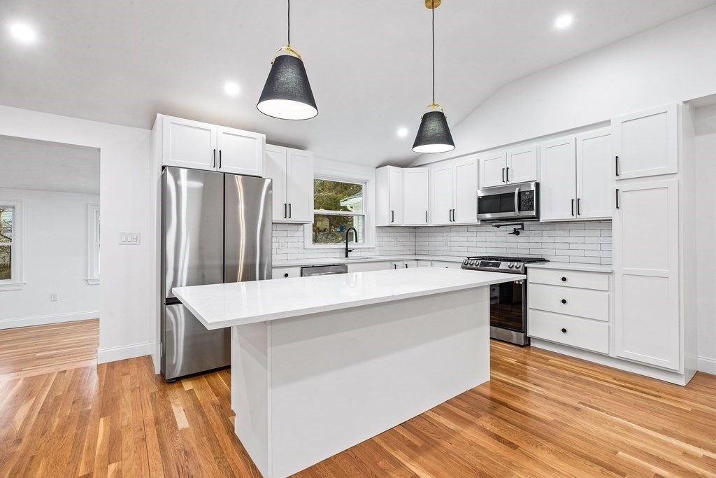 216 Grove Street Randolph, MA 02368 - Photo 10 of 34 a kitchen with stainless steel appliances kitchen island granite countertop a sink stove a refrigerator and white cabinets with wooden floor