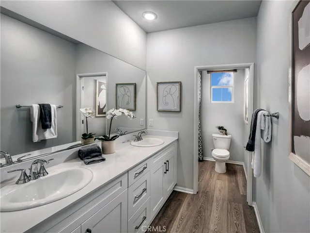 a spacious bathroom with a double vanity sink a mirror and toilet
