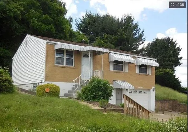 a aerial view of a house with yard and trees in the background