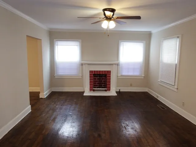 a view of an empty room with wooden floor fireplace and a window