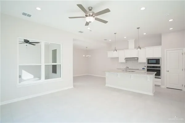 a large white kitchen with kitchen island a sink white cabinets and stainless steel appliances
