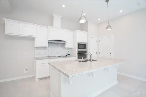 a kitchen with kitchen island a sink a stove a refrigerator and white cabinets