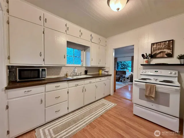 a kitchen with granite countertop a stove a sink and a microwave