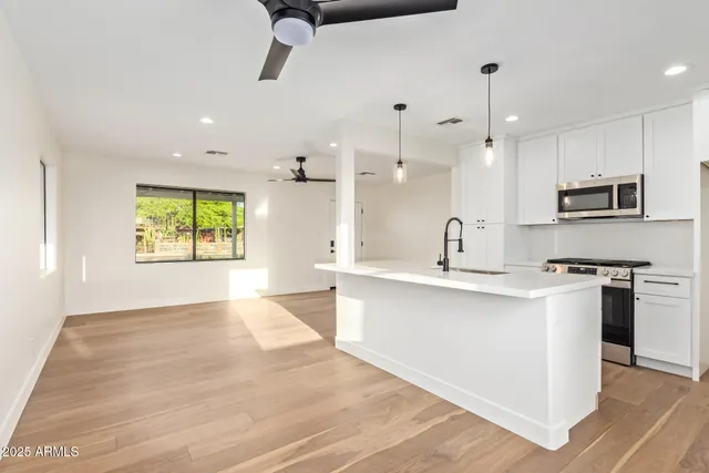 a large kitchen with stainless steel appliances kitchen island a large counter top and a wooden floors