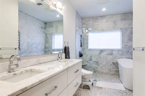 a bathroom with a double vanity sink toilet and a mirror