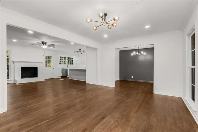 a view of an empty room with wooden floor and a fireplace