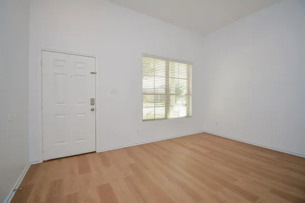 a view of an empty room with wooden floor and a window