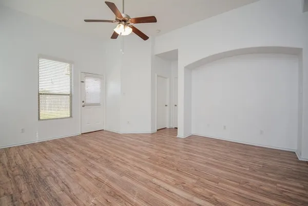 a view of empty room with wooden floor and fan