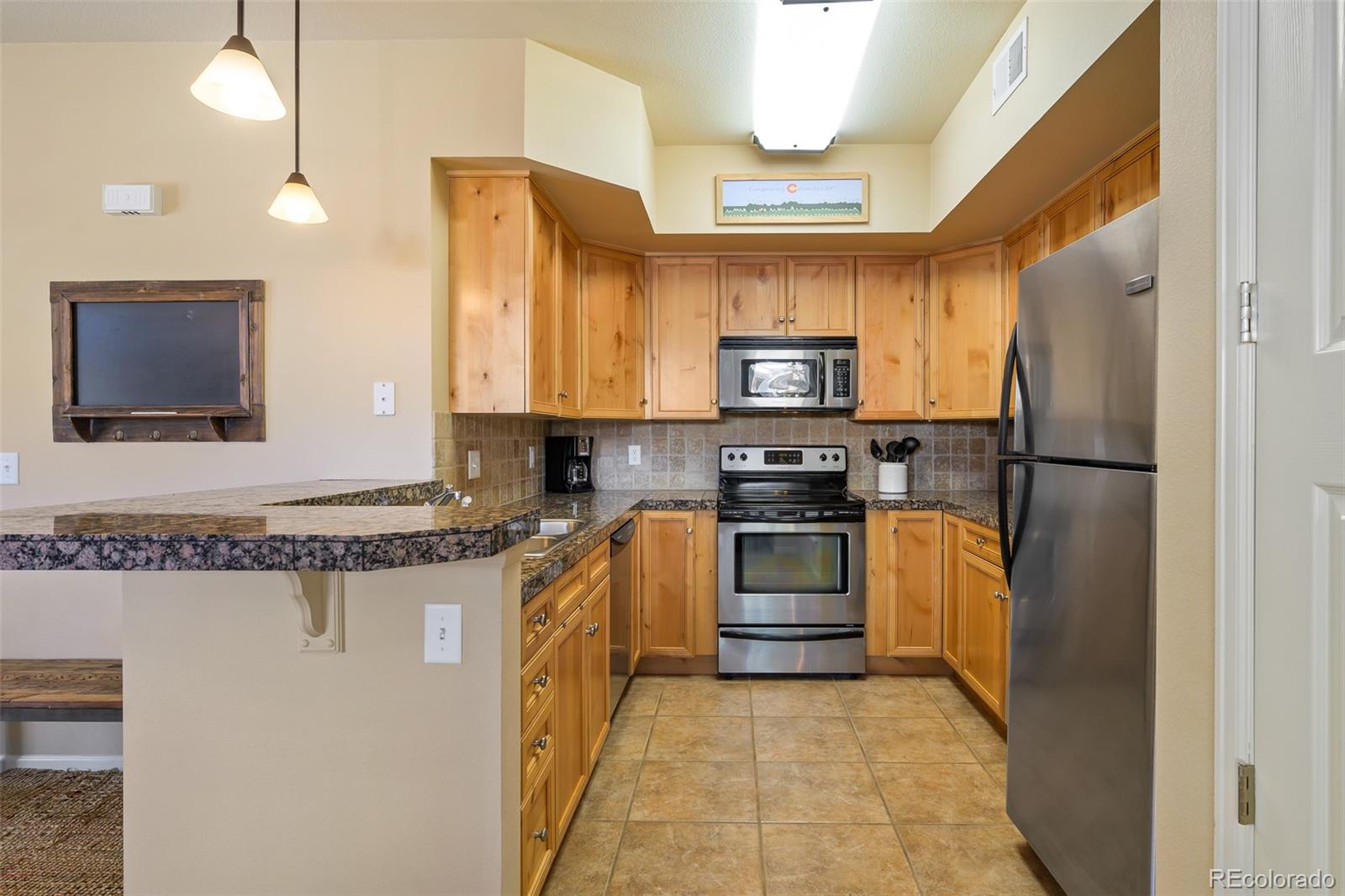 180 County Road, Unit 1 Fraser, CO 80442 - Photo 23 of 37 a kitchen with stainless steel appliances granite countertop a refrigerator stove and sink