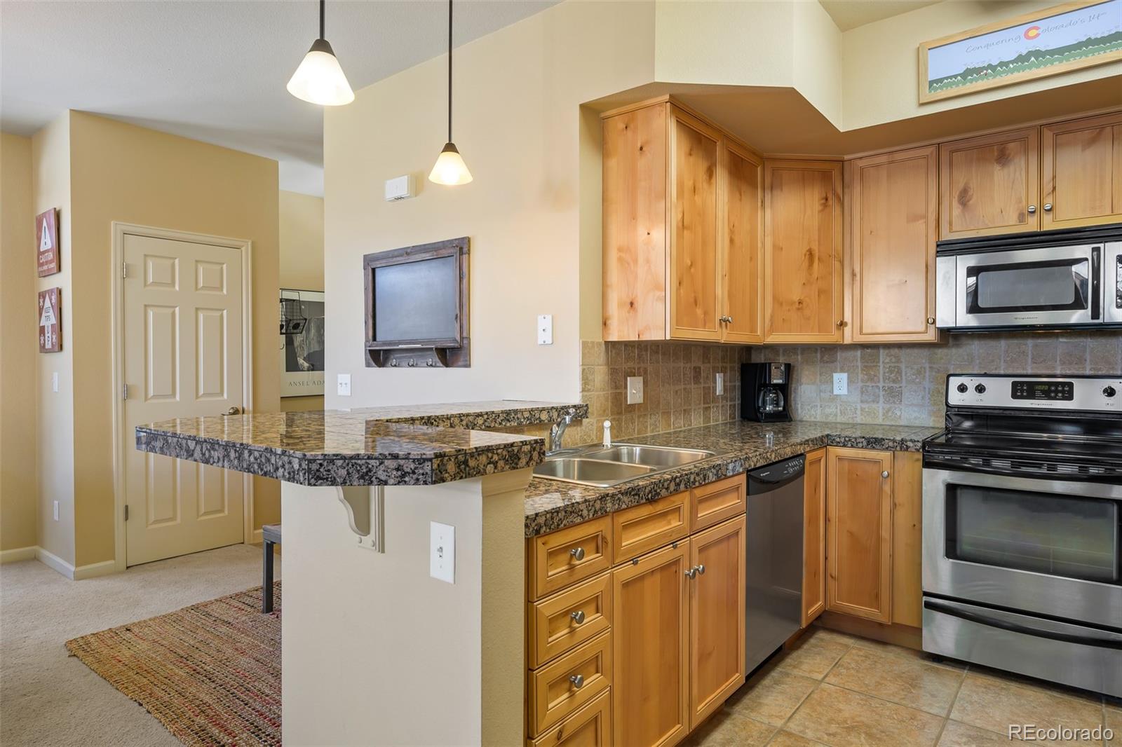 180 County Road, Unit 1 Fraser, CO 80442 - Photo 25 of 37 a kitchen with stainless steel appliances granite countertop a stove a sink and a microwave