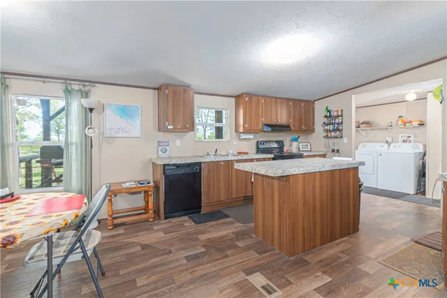 a kitchen with a refrigerator a stove a sink dishwasher with a dining table and chair