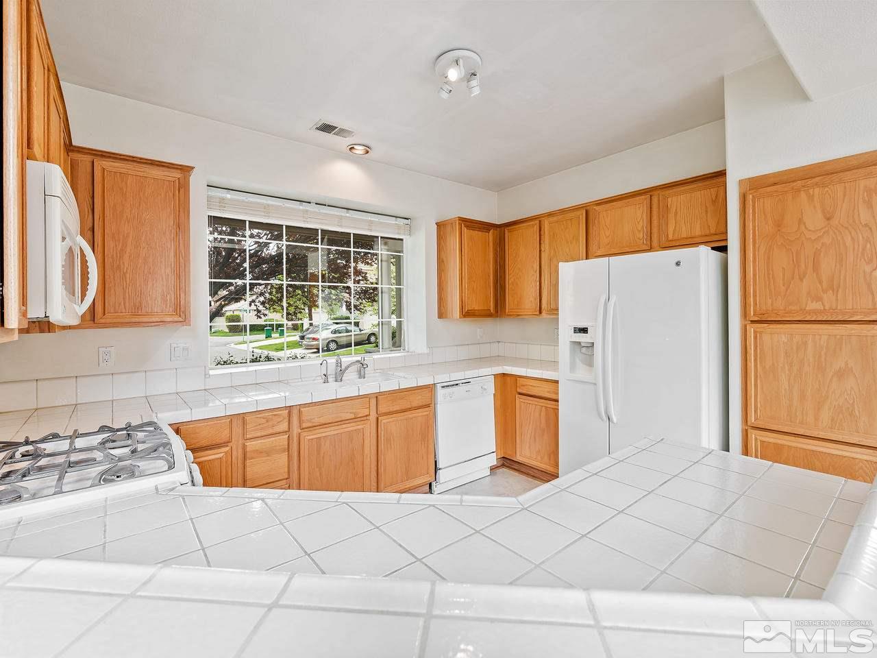 1287 Tule Drive Reno, NV 89521 - Photo 11 of 32 a kitchen with a refrigerator a stove top oven and a large window
