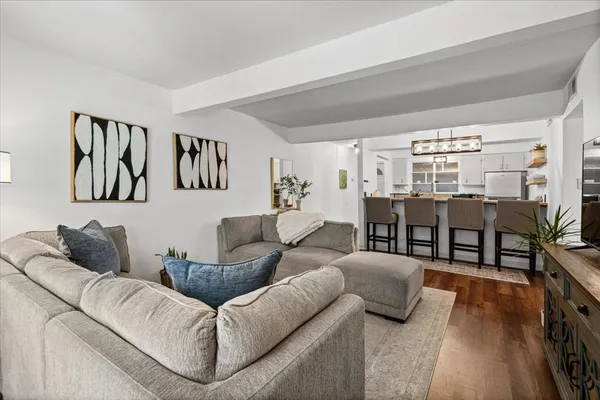 a living room with furniture a wooden floor and next to a window