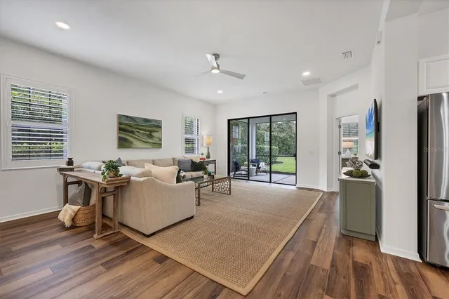 a living room with furniture a large window wooden floor and a rug
