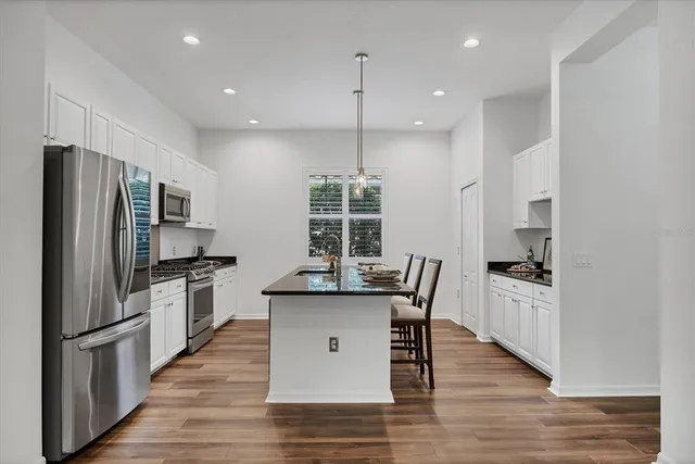 a kitchen with granite countertop kitchen island wooden floor center island and stainless steel appliances