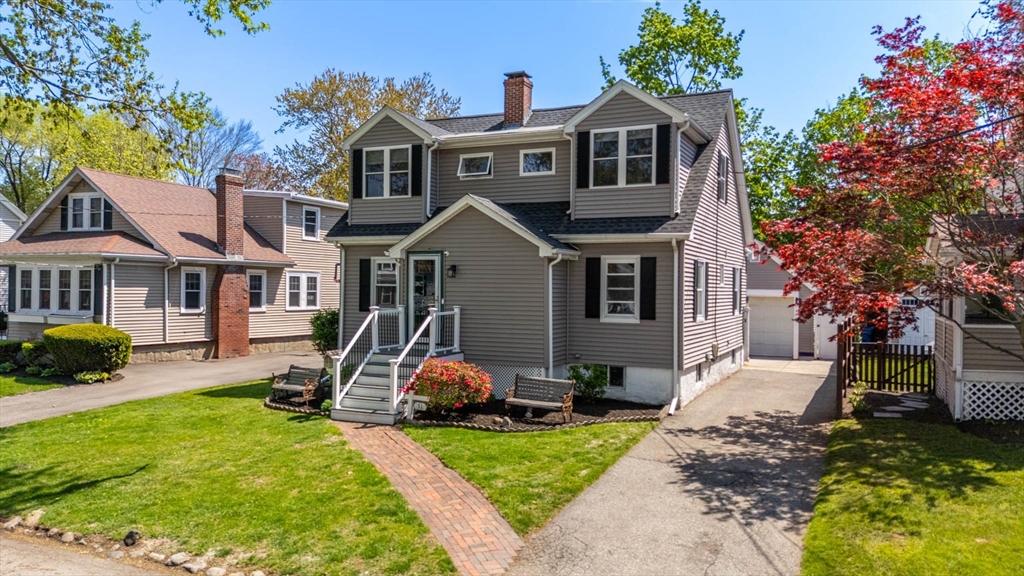 a front view of a house with a garden and trees