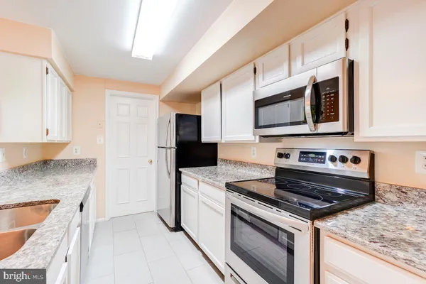 a kitchen with stainless steel appliances granite countertop a stove microwave and sink