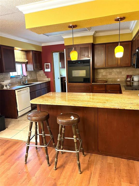 87 County Road Powderly, TX 75473 - Photo 5 of 9 Kitchen featuring black appliances, hanging light fixtures, a breakfast bar area, and a sink