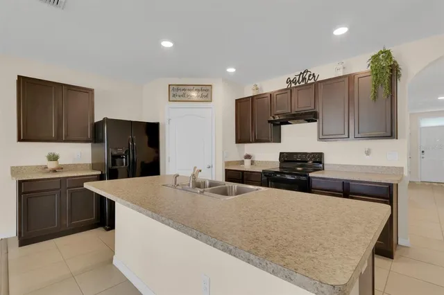 a kitchen with kitchen island granite countertop a sink counter top space appliances and cabinets