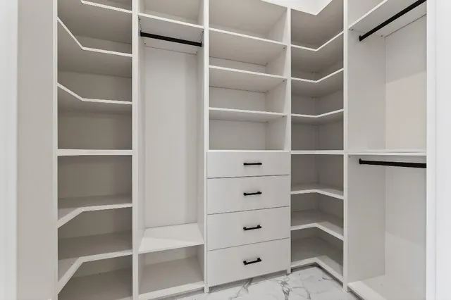 a view of walk in closet with clothes and shoes