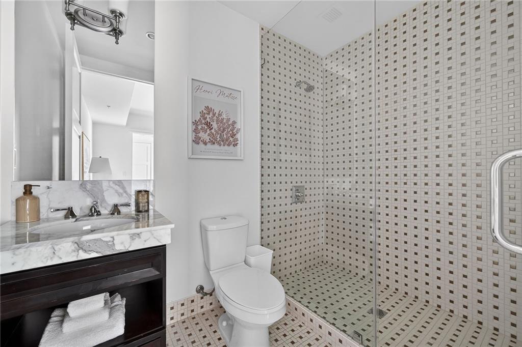 1820 Peachtree Road Northwest, Unit 312 Atlanta, GA 30309 - Photo 24 of 51 a bathroom with a granite countertop toilet a sink a mirror and a shower