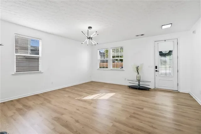 a view of an empty room with window and wooden floor