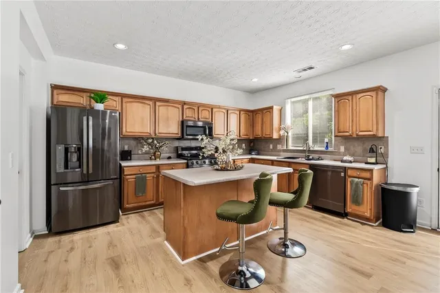 a kitchen with granite countertop stainless steel appliances a sink a counter top space cabinets and a window