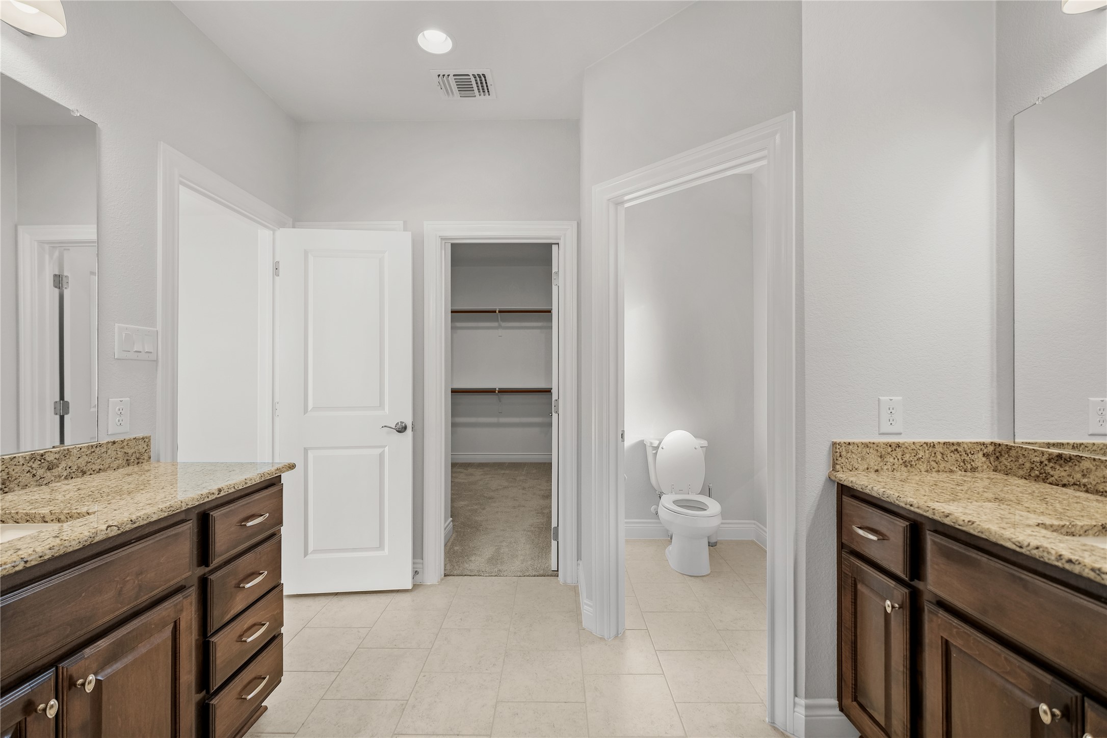955 Inka Road Salado, TX 76571 - Photo 10 of 39 Double vanities with stone counters flank the entryway to a walk-in closet and private toilet.