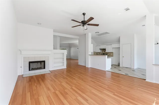 a view of a kitchen and an empty room with wooden floor
