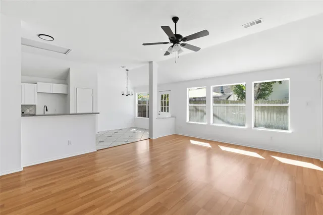 a view of empty room with wooden floor and fan
