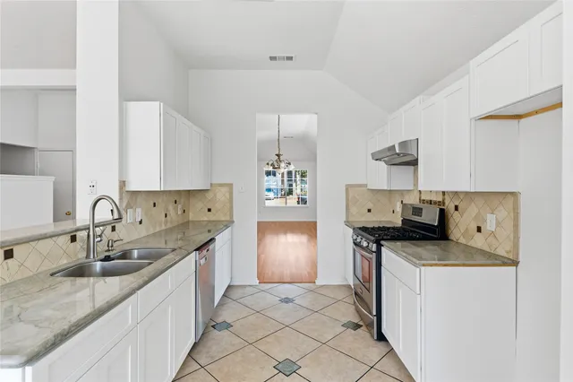 a kitchen with granite countertop a sink stove and cabinets