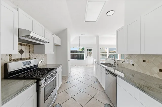 a kitchen with stainless steel appliances granite countertop a sink stove and cabinets