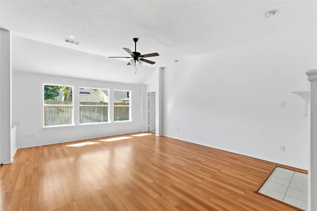 a view of an empty room with a window and wooden floor
