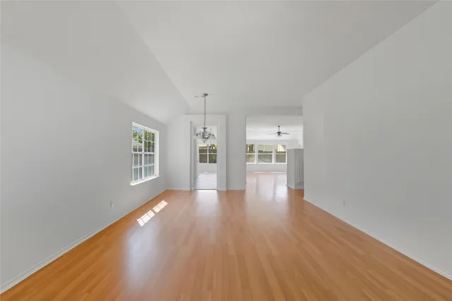 a view of empty room with wooden floor and windows