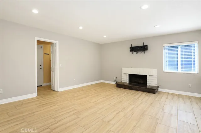 a view of empty room with wooden floor and fireplace