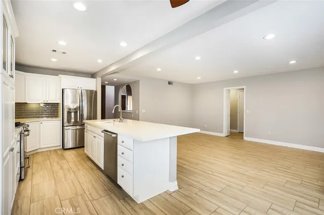 a large kitchen with stainless steel appliances kitchen island a large counter top and a wooden floors