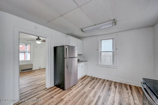 a view of kitchen with refrigerator cabinets and wooden floor