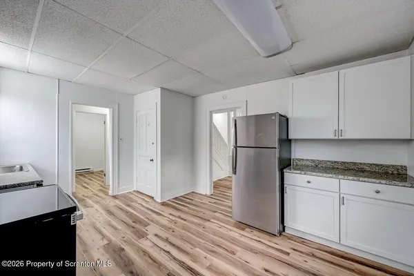 a kitchen with stainless steel appliances granite countertop a refrigerator a stove a sink and white cabinets